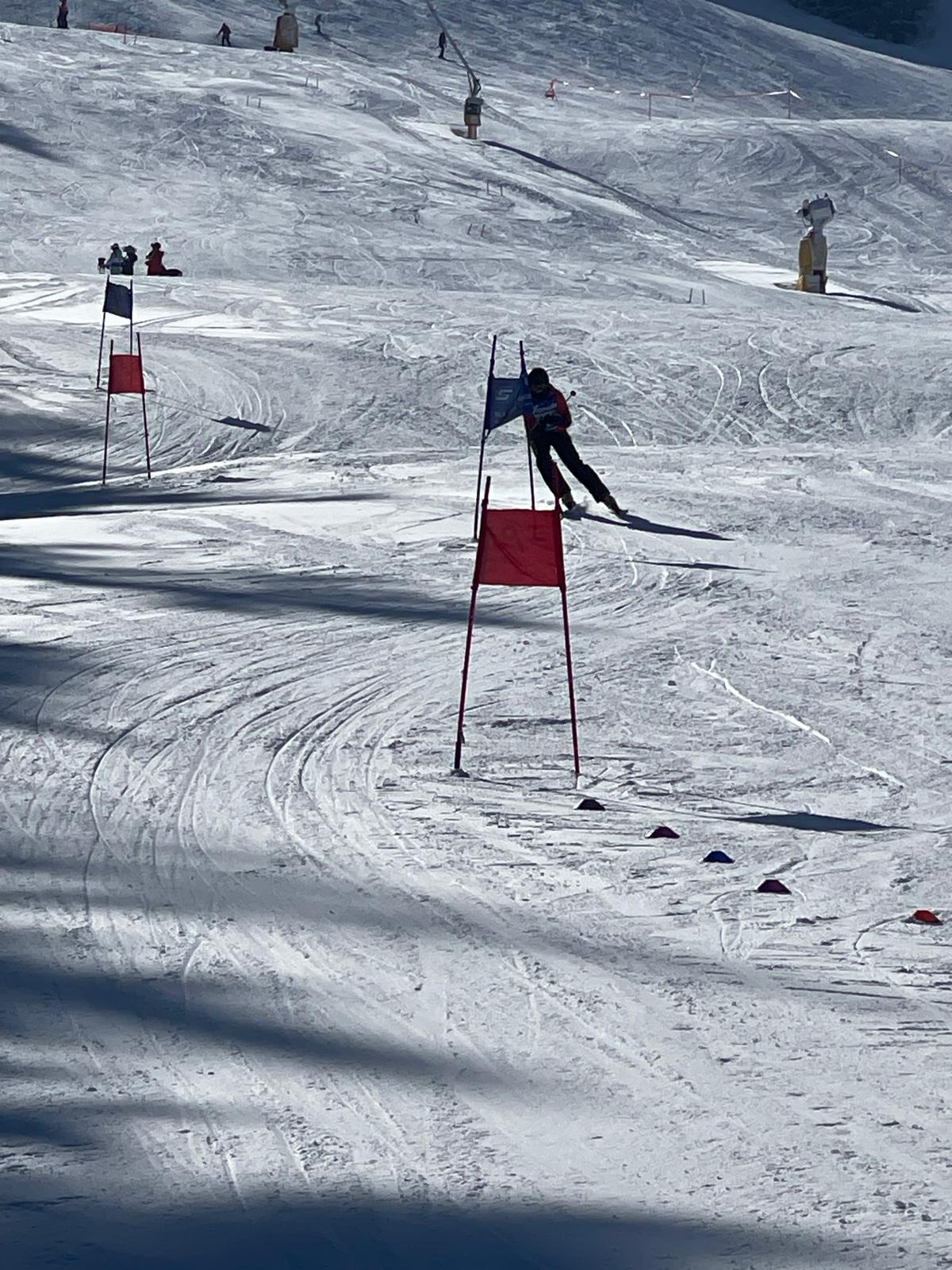 A racer carving between blue and red giant slalom gates on a groomed race course